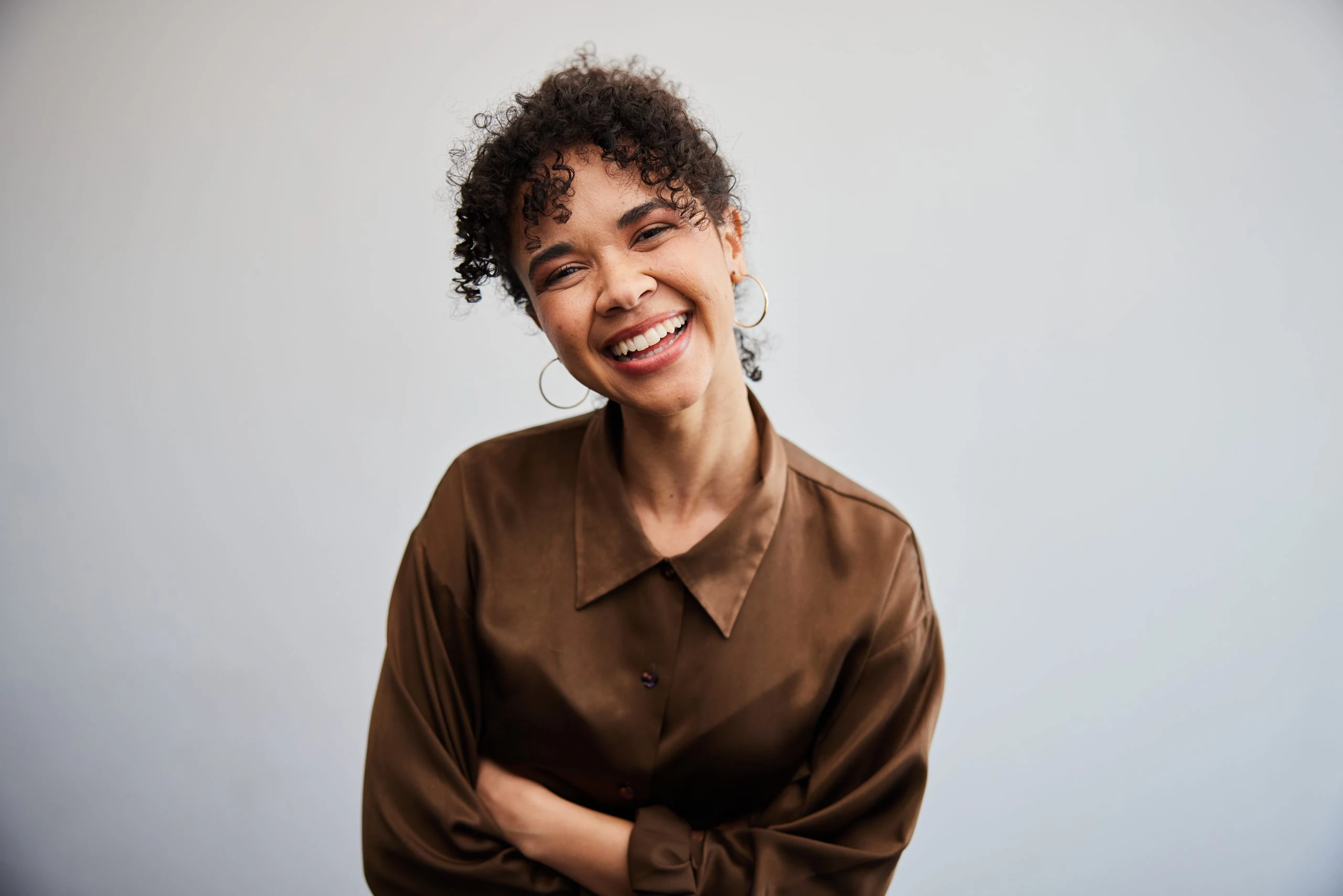 Laughing young businesswoman standing in front of an office wall